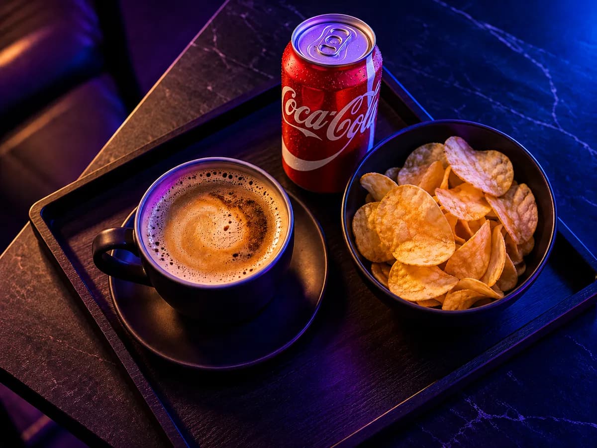 A tray with a cup of coffee, a bowl of chips and a can of cola
